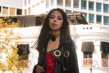 Stylish woman in vibrant attire against historic Puebla, Mexico cityscape.